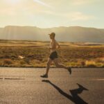 man in black shorts running on gray asphalt road during daytime