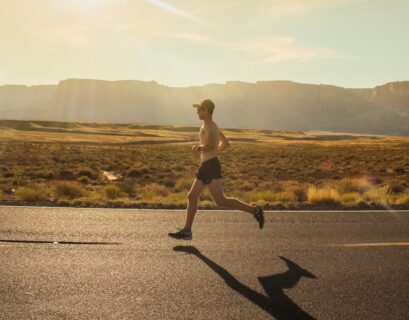 man in black shorts running on gray asphalt road during daytime