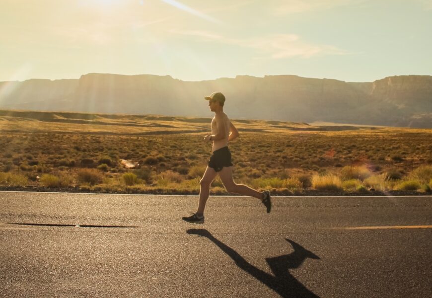 man in black shorts running on gray asphalt road during daytime