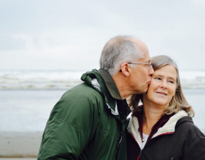 man kissing woman on check beside body of water