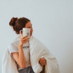 woman in white robe holding white ceramic mug