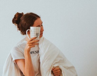 woman in white robe holding white ceramic mug