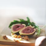 sliced in half oval green fruit above wooden chopping board