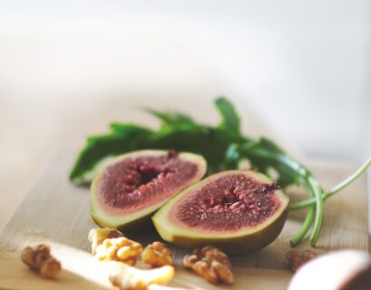 sliced in half oval green fruit above wooden chopping board