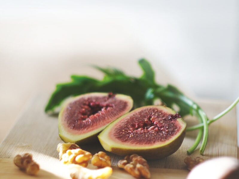 sliced in half oval green fruit above wooden chopping board