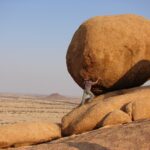 man standing beside rock formation