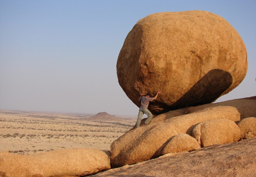 man standing beside rock formation