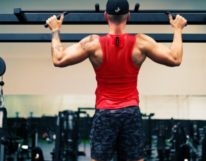 man in red tank top and black shorts holding black dumbbell