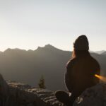 person wearing knit cap facing mountain