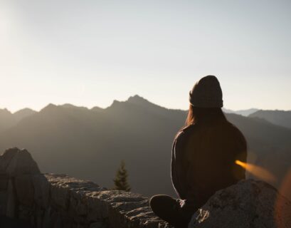 person wearing knit cap facing mountain