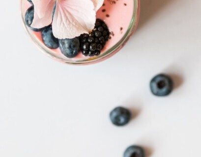 pink beverage on glass with blackberries and pink flower on top