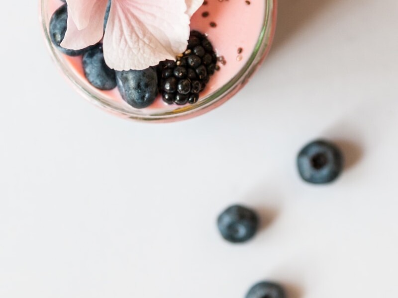 pink beverage on glass with blackberries and pink flower on top