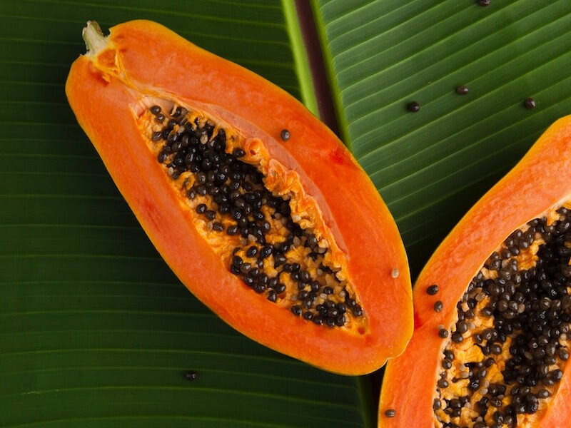 sliced papaya on green banana leaf